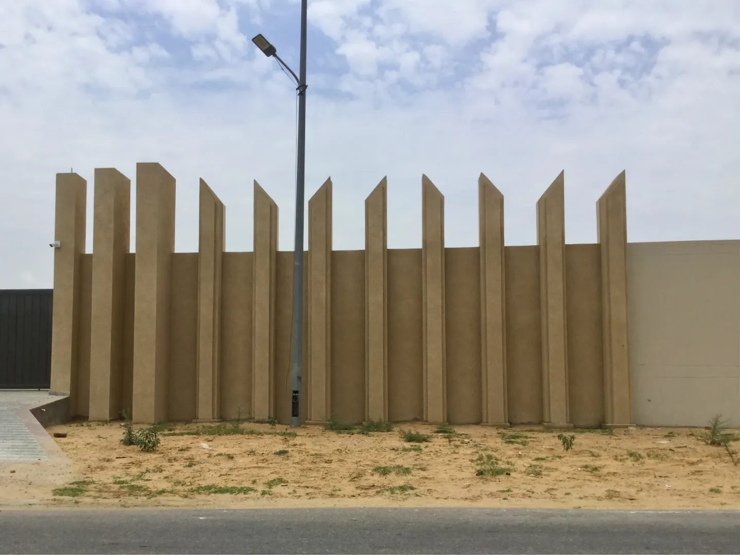 Deep vertical concrete fins shading a pale wall under a bright sky.