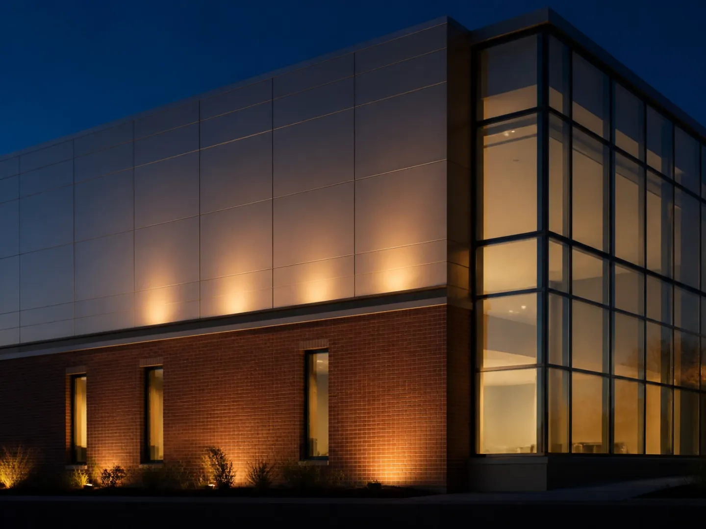 Brick, metal rainscreen and glass curtain-wall systems meeting on one facade.