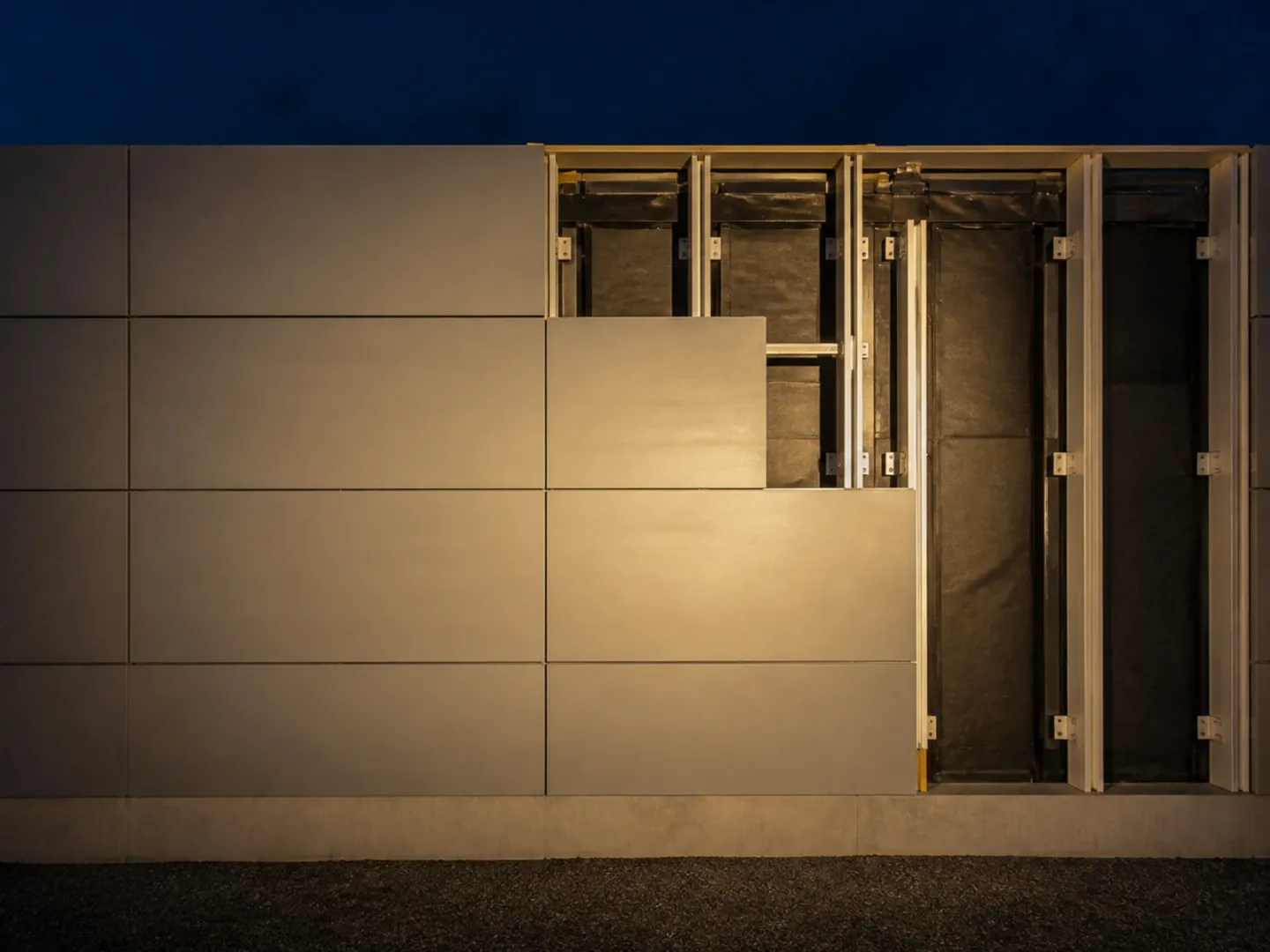 Open rainscreen panel bay showing aluminium rails and a drainage cavity.